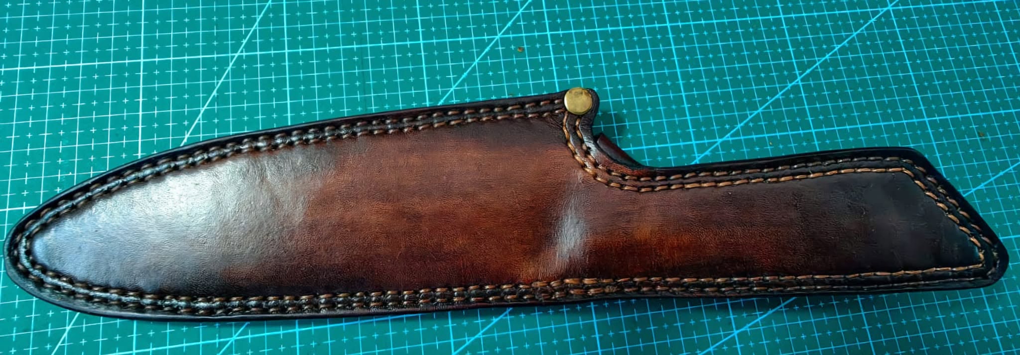 Dark brown leather knife sheath with decorative stitching